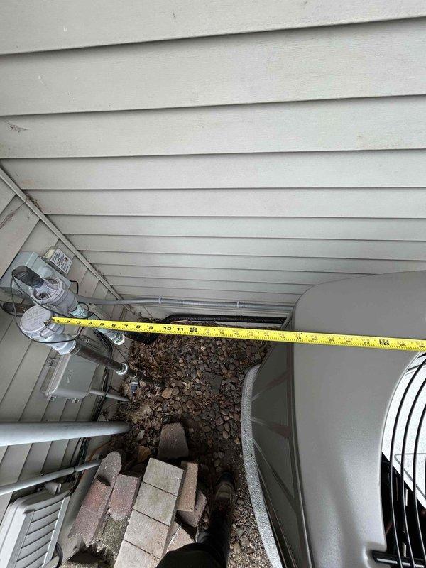 Responded to install callback for recently installed outdoor HVAC system that was positioned too close to garage door entrance, with condensing unit and equipment pad partially obstructing concrete walkway. Assessed clearances and measured distances between unit, house siding, and garage door swing path. Coordinated with install crew to relocate condensing unit and equipment pad approximately 12-18 inches closer to house foundation and off concrete entrance area to resolve door clearance issue and restore full access to garage. Verified proper clearances maintained for equipment serviceability and airflow requirements. Documented final positioning with measurements and photographs showing adequate spacing from structure and unobstructed garage access.