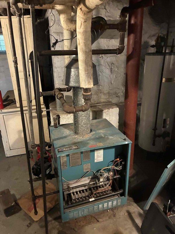 Performed comprehensive boiler inspection and maintenance on 1980s-era heating system serving five-unit residential property. Cleaned burners and burner box thoroughly. Observed that gas valve, control board, circulating pump, and aquastat had been replaced within recent years and were in acceptable operating condition. Bled all radiators throughout all five apartments and verified heat distribution to each unit.

Identified three flow valve leaks during inspection. Found one flow valve in upper apartment (unit 4) with significant leak; associated black iron piping exhibited severe corrosion and deterioration, making valve replacement impractical without complete pipe replacement. Attempted to mitigate leak by tightening packing nut. Discovered two additional flow valves in apartment 2 with minor leaks. 

Confirmed single thermostat in apartment 3 controls entire building heating system. All radiators bled successfully and verified proper heating operation across all units. Advised pro