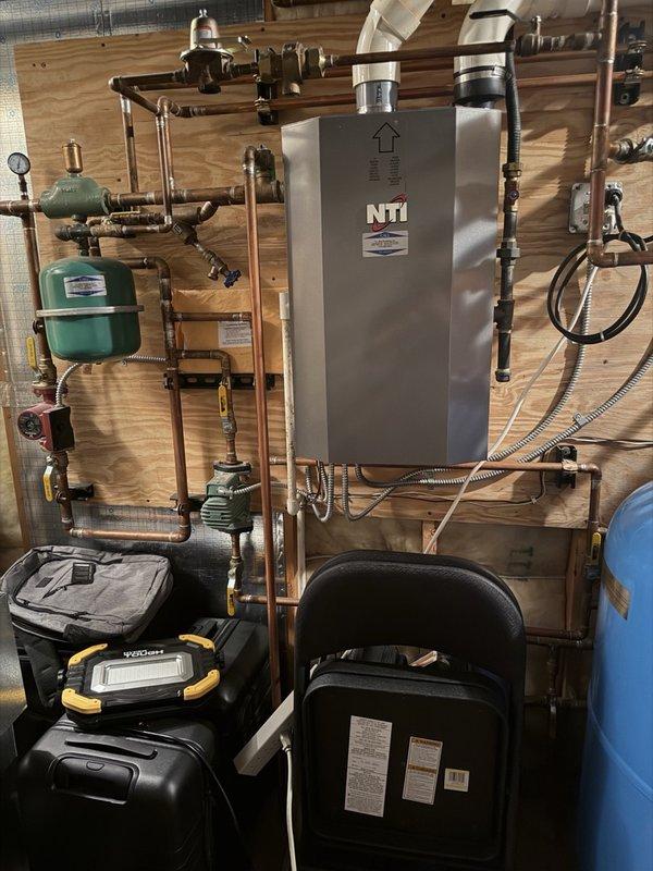 Completed comprehensive plumbing inspection including evaluation of dripping shower head in spare bathroom and full system assessment. Inspected tankless water heater unit, expansion tanks, circulation pump, pressure gauges, copper piping network, valves, and all associated connections for proper operation and potential issues. Documented mechanical room installation and plumbing system components with diagnostic equipment to ensure all fixtures and heating system elements are functioning within normal parameters.