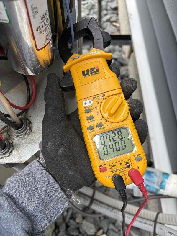 Responded to no cooling complaint with system drawing excessive electricity. Upon arrival, verified thermostat calling for cooling properly. Inspected outdoor unit and found condenser fan motor operating but compressor not running. Tested dual run capacitor (45+5 MFD) and confirmed readings were out of manufacturer specifications, preventing compressor from starting.

Recommended capacitor replacement to restore system operation. Installed new dual run capacitor provided by homeowner. After replacement, verified all electrical components operating correctly using clamp meter. Measured compressor amp draw and fan motor amp draw, both reading within manufacturer specifications. Checked indoor blower motor operation and confirmed proper amp draw.

Measured supply and return air temperatures and calculated temperature split of 23 degrees, confirming adequate cooling performance. System restored to normal cooling operation with all components functioning properly.