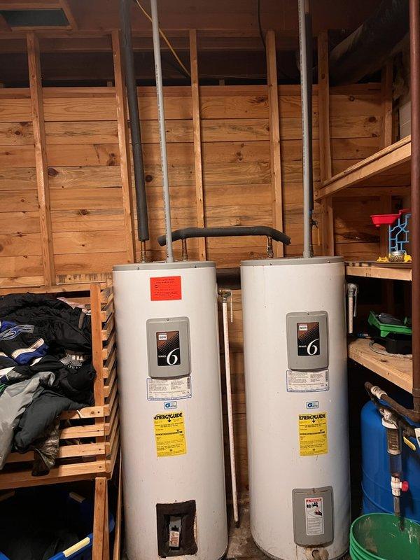 Removed and disposed of two aging, leaking 26-year-old electric tank water heaters that were short-cycling and delivering only about 10 minutes of hot water. Since the whirlpool tub they served is out of service, the system was consolidated to a single new 50-gallon electric water heater, which was installed, connected, and tested for proper heating and leak-free operation.