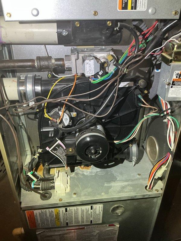 Performed a full maintenance tune-up on a 15-year-old Bryant forced air furnace, including electrical testing of components with a clamp multimeter and inspection of the cabinet interior. The heat exchanger passed inspection, but the draft inducer motor/housing area was flagged as a suspected leak, with rust and corrosion staining observed on the cabinet floor beneath the inducer assembly. Recommended further evaluation of the inducer assembly to confirm the leak and prevent continued corrosion.