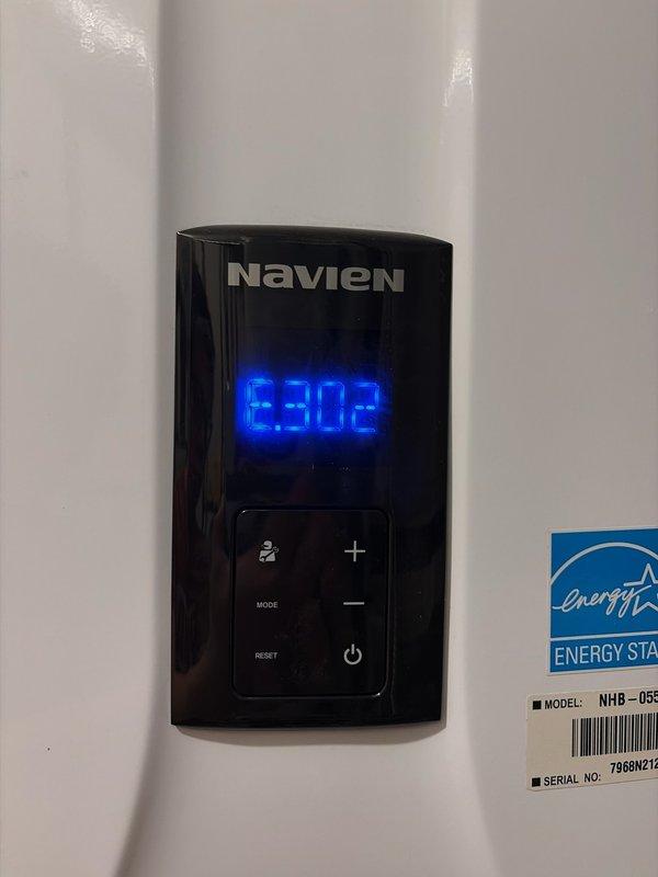 Diagnosed the garbage disposal as non-functional due to a seized motor causing jamming and excessive noise; removed the failed unit and installed a new disposal. Also inspected the Navien tankless water heater, which displayed an E302 error code on the control panel while operating normally, with no visible damage, corrosion, or leaks observed at the unit or its connections.