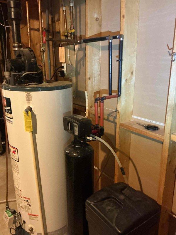 Inspected the existing water softener, which was not drawing salt from the brine tank and was no longer delivering softened water. Evaluated the control valve, resin tank, brine tank, and plumbing connections, and determined the unit is older and undersized for the household demand. Assessed the adjacent power-vent water heater and surrounding piping, and documented existing equipment to prepare estimates for a replacement softener, carbon filtration tower, and water heater.