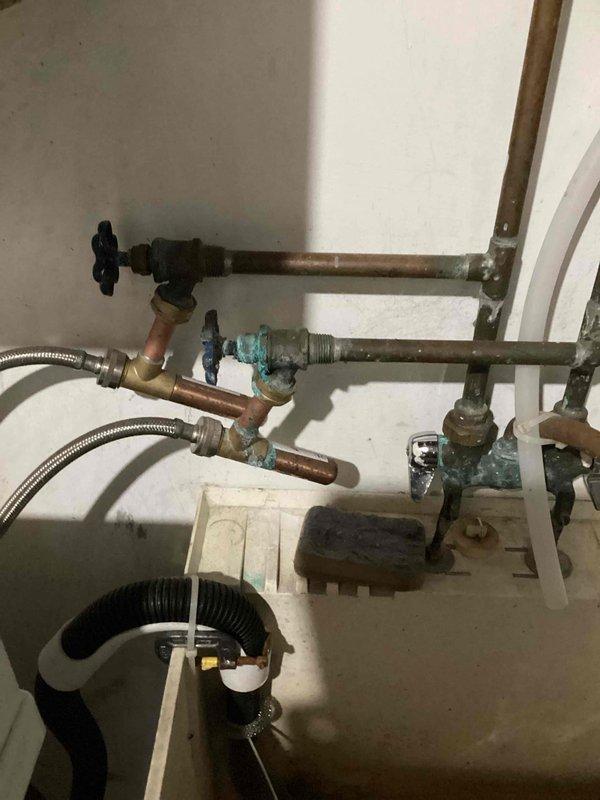 Performed a member plumbing inspection and evaluated the gas water heater, which is well past its serviceable life (10+ years) and recommended for replacement. Noted corrosion and verdigris buildup on copper supply piping, valves, and fittings in the utility area, and assessed the slow-draining downstairs bathroom sink for drain restriction.