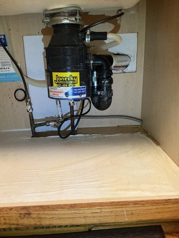 Diagnosed the garbage disposal as failed and leaking, then disconnected and removed the unit from the sink drain assembly and discharge connection. The under-sink supply lines and drain trap were left intact, and the area was inspected afterward. The toilet supply line and angle stop showed no visible leaks, though a flange or wax ring failure at the toilet base remains a suspected source of the moisture in the surrounding tile.