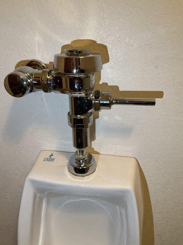 Responded to a wall-mounted urinal that ran continuously and required the water supply to be shut off to stop it. Diagnosed the chrome flush valve as worn and at end of life, causing the constant running. Submitted a parts order for a replacement urinal flush valve.