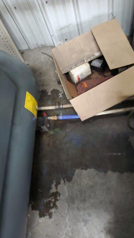 Responded to an active water leak at the backflow preventer assembly, which was discharging heavily enough to fill a 5-gallon bucket and had saturated the surrounding concrete floor. Inspected the backflow device and adjacent brass relief valve and piping, noting corrosion and mineral residue at the threaded connections. Submitted a parts order for a backflow preventer rebuild kit to restore proper sealing and complete the repair.
