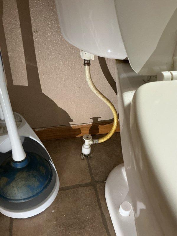 Performed a plumbing inspection of the bathroom toilet and its supply components, confirming the braided flexible supply line and shut-off valve were properly connected with no visible leaks, corrosion, or damage. Also inspected the gas furnace installation, including the gas supply line and shutoff valve, PVC venting, and condensate drain tubing, noting peeling warning labels on the cabinet but no apparent leaks or defects in the plumbing and gas connections.