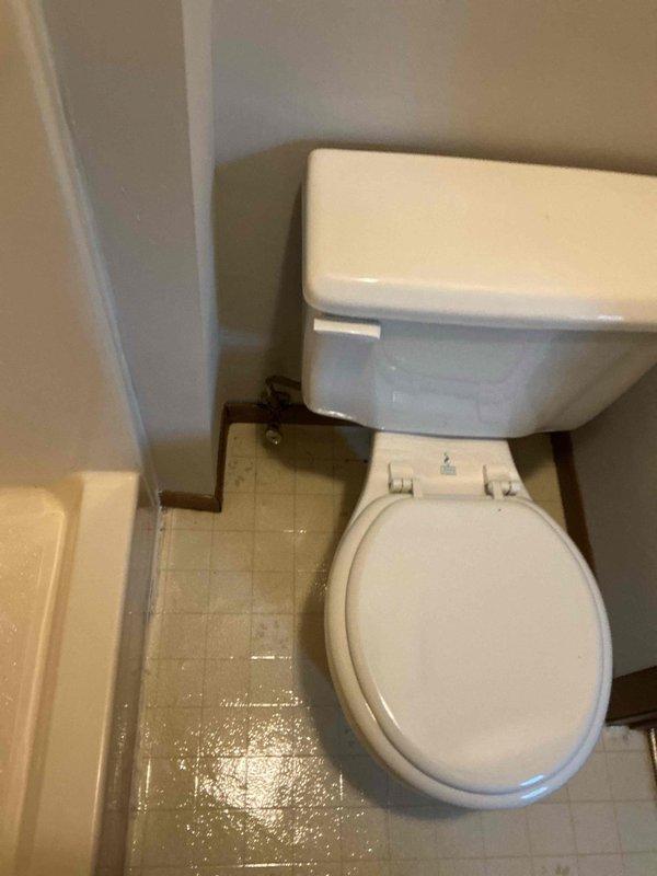 Responded to a reported toilet leak and inspected the unit, identifying a drip at the supply shutoff valve. Tightened the packing nut on the shutoff valve to stop the leak and confirmed the valve and supply connection were dry and holding with no further dripping.