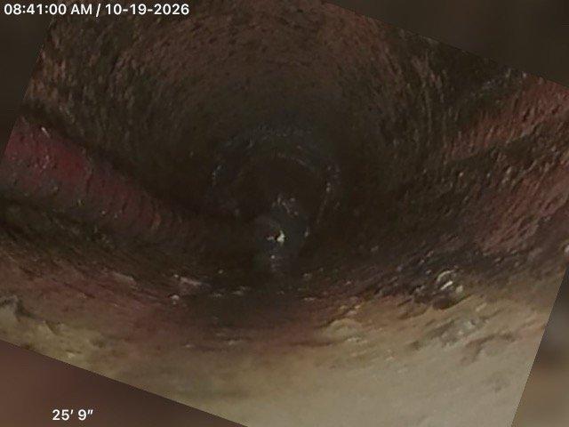 Responded to a main drain backup with standing water in the basement and a backing-up floor drain. Cleared the main sewer line of root intrusion using drain cleaning equipment, restoring flow. Performed a post-cleaning camera inspection that revealed heavily corroded, scaled pipe walls with sediment buildup at approximately 25' to 27' from the access point.