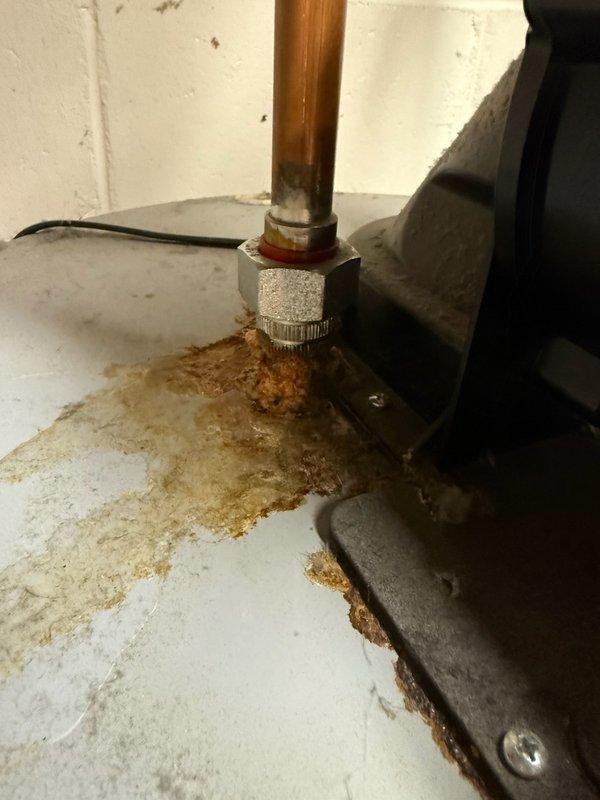 Diagnosed a 2019 gas tank-style water heater with calcified, corroded top nipples and fittings leaking at the hot and cold connections, causing heavy rust and mineral deposits across the tank top. Confirmed the corrosion was beyond repair and the unit required replacement, which was approved and sold.