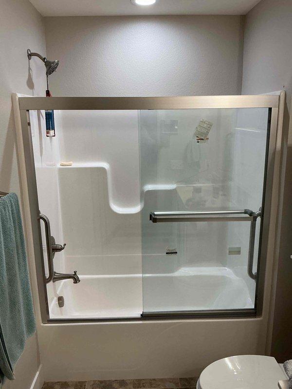Installed a customer-supplied sliding glass shower door with a brushed nickel frame and towel bar handle on the one-piece fiberglass tub and shower enclosure. Secured and aligned the door for proper operation, and verified smooth sliding action with no visible damage to the enclosure or surrounding fixtures.