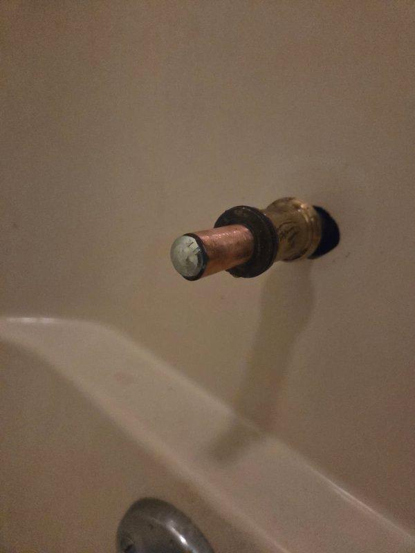 Removed a seized bolt lodged in the tub spout supply nipple and extracted the corroded spout adapter that was preventing installation of the replacement fitting. Inspected the exposed copper stub-out and brass coupling, which showed tarnish and oxidation, then prepared the pipe end for a proper seal and verified it was ready to accept the new tub spout.