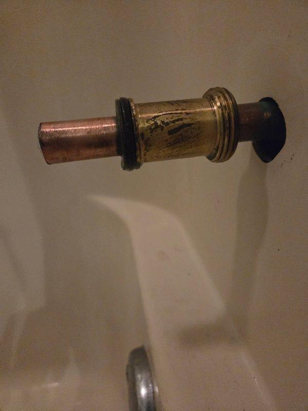 Removed a seized bolt lodged in the tub spout supply nipple and extracted the corroded spout adapter that was preventing installation of the replacement fitting. Inspected the exposed copper stub-out and brass coupling, which showed tarnish and oxidation, then prepared the pipe end for a proper seal and verified it was ready to accept the new tub spout.