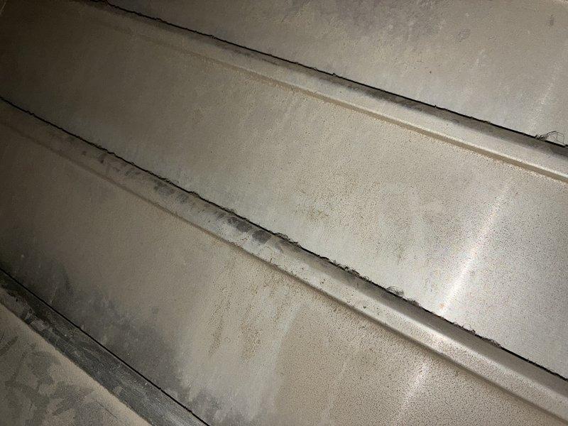 Responded to a no-cool call and found the evaporator coil frozen, with a coil temperature in the 20s. System refrigerant charge was low, and high- and low-side pressures were fluctuating in unison. After blocking the shared return pathway to rule out airflow interaction from the furnace fan louvers, pressure fluctuation persisted on one unit while the second unit operated normally, indicating a slow refrigerant leak and a probable refrigerant restriction. Photos document dust accumulation and rust staining in the return ductwork; the homeowner is evaluating leak repair options versus system replacement.