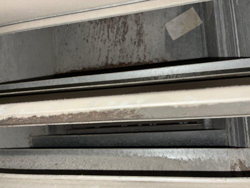 Responded to a no-cool call and found the evaporator coil frozen, with a coil temperature in the 20s. System refrigerant charge was low, and high- and low-side pressures were fluctuating in unison. After blocking the shared return pathway to rule out airflow interaction from the furnace fan louvers, pressure fluctuation persisted on one unit while the second unit operated normally, indicating a slow refrigerant leak and a probable refrigerant restriction. Photos document dust accumulation and rust staining in the return ductwork; the homeowner is evaluating leak repair options versus system replacement.