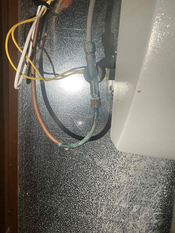 Performed a biannual plumbing inspection of exposed copper supply lines, valves, and fittings in the basement utility area, finding the lines and shutoff valve generally intact with some surface oxidation. Identified heavy verdigris corrosion on a copper line and brass compression fittings at the equipment cabinet, indicating a possible slow leak or connection deterioration; recommend further evaluation and fitting replacement or tightening to prevent water damage.
