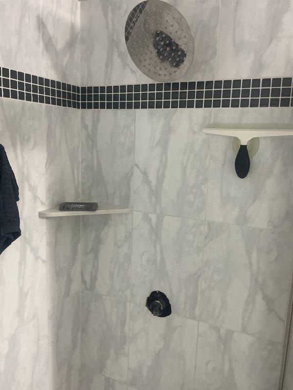 Diagnosed a pinhole leak in the supply line serving the shower head, located approximately 1/2" above the shower valve. Inspected the tiled shower stall with the valve trim and handle removed to access the affected area, and evaluated repair versus replacement options for the damaged section of pipe.