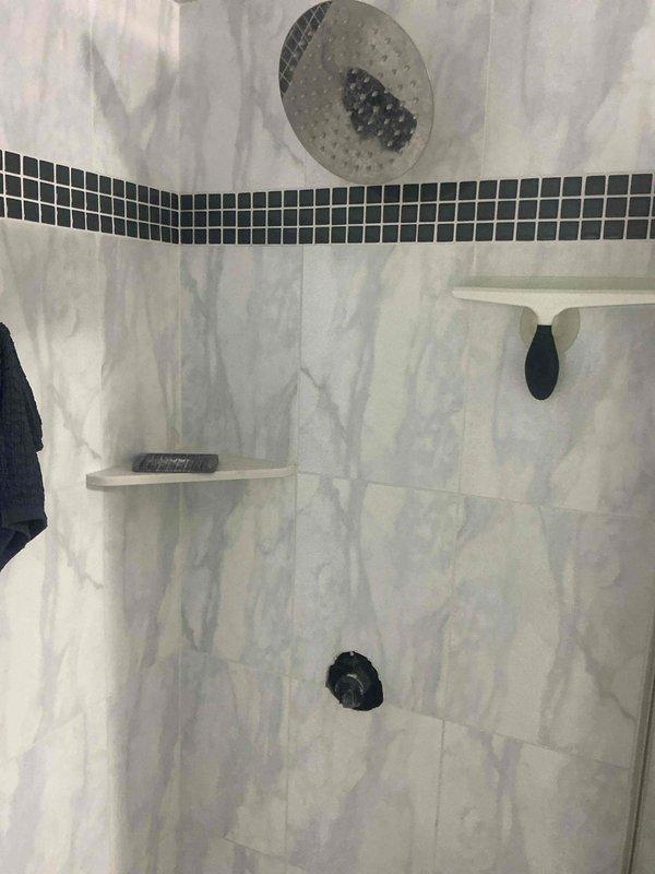 Diagnosed a pinhole leak in the supply line serving the shower head, located approximately 1/2" above the shower valve. Inspected the tiled shower stall with the valve trim and handle removed to access the affected area, and evaluated repair versus replacement options for the damaged section of pipe.