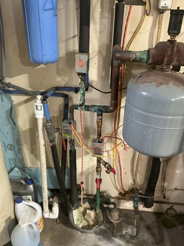 Completed estimate for gas boiler replacement in garage mechanical room. Assessed existing hydronic heating system showing significant age-related deterioration including corroded piping, rusted expansion tank, and aged circulation pump. Documented current installation featuring galvanized steel piping with surface oxidation, blue expansion tank with visible rust staining, red/black circulation pump, water filtration system, and various control valves in deteriorated condition. Provided comprehensive replacement recommendations and captured photographic documentation of all equipment and components for customer review.