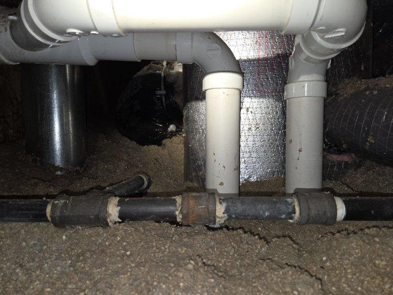 Responded to service call for water leaking from ceiling originating in attic area. Upon inspection, discovered condensation accumulation on HVAC ductwork and associated plumbing systems in attic space. Examined white PVC condensate drain lines and U-trap configuration, noting dust and dirt buildup on piping surfaces. Inspected black metal manifold distribution system and surrounding electrical routing. Assessed reflective silver ductwork insulation showing moisture droplets and condensation on metallic surface, indicating potential insulation degradation or inadequate vapor barrier. Evaluated horizontal black pipe with visible mineral deposits and white residue suggesting ongoing moisture issues. Photographed affected areas including PVC plumbing configuration, gray elbow fittings, and condensate management system. Documented conditions of confined attic utility space where HVAC, plumbing, and electrical systems converge. Identified condensation on ductwork insulation as primary sourc
