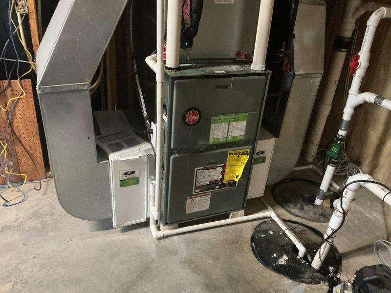 Conducted on-site evaluation of non-operational air conditioning system while furnace remained functional. Assessed existing teal-colored outdoor condensing unit and indoor HVAC system components including gray Rheem furnace with connected ductwork, humidifier, and PVC condensate drainage. Documented current equipment condition through photographic records of both basement installation and exterior unit placement. Provided comprehensive replacement estimate for AC unit only, as furnace system was verified to be operating properly and did not require replacement at this time.