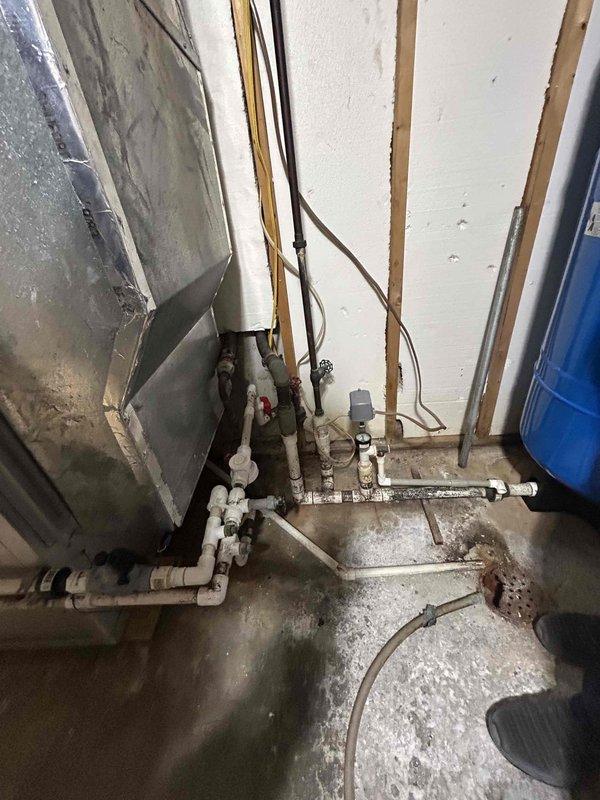 Conducted on-site assessment of existing HVAC system located in unfinished basement utility area for equipment replacement estimate. Documented current installation conditions including aged air handler unit with visible dust accumulation, exposed ductwork, and utility infrastructure. Evaluated accessibility for equipment removal and new system installation, noting concrete floor conditions, existing plumbing lines, electrical routing along wall studs, and available clearances for proper equipment placement and service access.