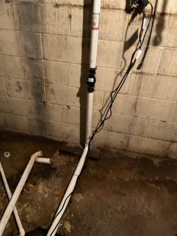 Conducted follow-up assessment of basement utility systems per previous technician's recommendations. Inspected tanked water heater showing significant age-related deterioration, including extensive rust formation on tank exterior and corroded copper supply lines. Evaluated sump pump operation in response to reported noise issues. Documented moisture damage on basement floor and foundation walls indicating potential drainage concerns. Photographed water heater condition and surrounding plumbing infrastructure to support replacement recommendations for aging equipment.