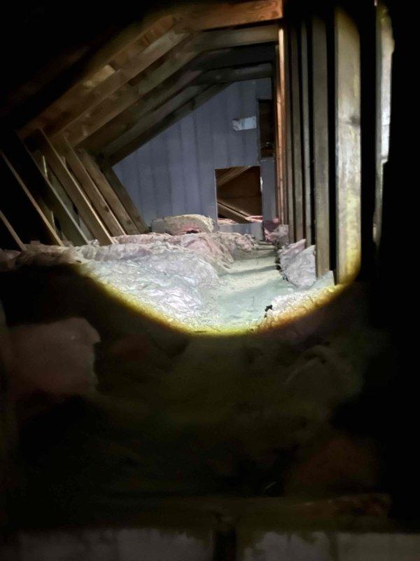 Completed estimate for HVAC system conversion from electric heat to gas furnace and central air conditioning in home with no existing ductwork. Assessed attic space with exposed rafters and fiberglass insulation for potential supply duct routing and register placement. Evaluated unfinished basement area with concrete floor and brick support columns for equipment installation location and return air system design. Photographed existing conditions including structural framing, insulation, available clearances, and utility access points to develop comprehensive ductwork layout and equipment specifications for full system installation.