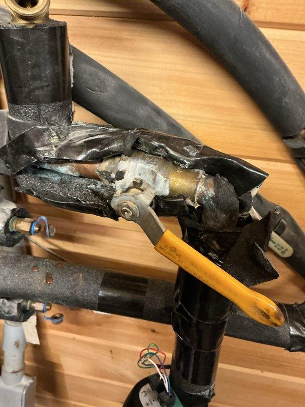 Completed first prepaid cooling system maintenance visit. Upon arrival, addressed customer concern regarding a broken handle from previous service visit that was never repaired or replaced. Performed comprehensive inspection of air handler unit, examining blower motor assembly, electrical connections, and wiring harness. All wire bundles were properly secured with zip ties and connections were verified at terminal blocks. Inspected motor housing, fan blades, and internal components for proper operation. 

During exterior unit inspection, discovered severe heat damage to refrigerant line service valve assembly. The valve housing showed extensive thermal stress with metal casing ruptured, peeled back, and melted, exposing internal brass fittings. Black insulated refrigerant lines and foam insulation exhibited signs of extreme heat exposure. This damage indicates a critical failure that occurred during previous operation or service work, rendering the affected component non-functional and