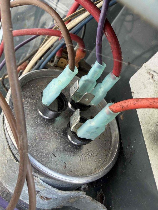Completed prepaid cooling season maintenance check on residential air conditioning system. Performed electrical diagnostics using digital multimeter to verify proper voltage and amperage readings across capacitor and associated wiring connections. Inspected capacitor with multiple wire terminations, confirmed all spade connectors secure with proper heat-shrink insulation, and verified system operational parameters within manufacturer specifications.