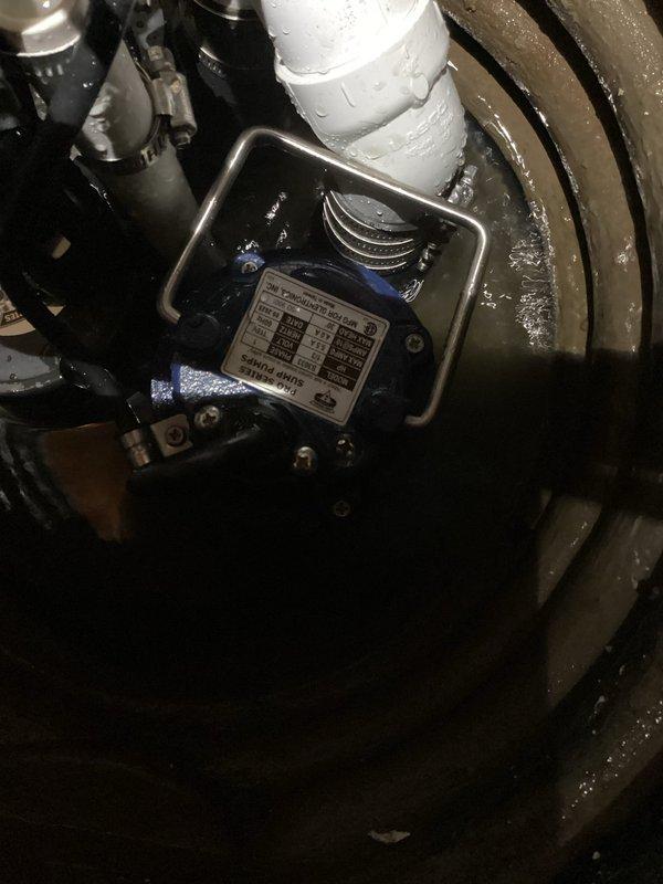 Installed PHCC battery backup combination sump pump system in basement sump basin. The installation included mounting the primary blue pump unit in the circular concrete basin, connecting multiple discharge pipes including white PVC piping, and routing electrical cables for power supply. Configured the battery backup system to provide emergency pumping capability during power outages, ensuring continuous flood protection for the property.