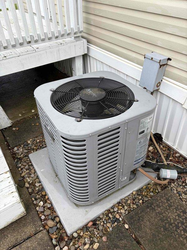 Completed first-year cooling tune-up on residential outdoor condensing unit. Performed comprehensive inspection of electrical connections, noting corrosion on terminal block screws and accumulated debris on components. Unit operational with adequate airflow through vertical louvers; system running within normal parameters on concrete pad with proper clearances maintained.