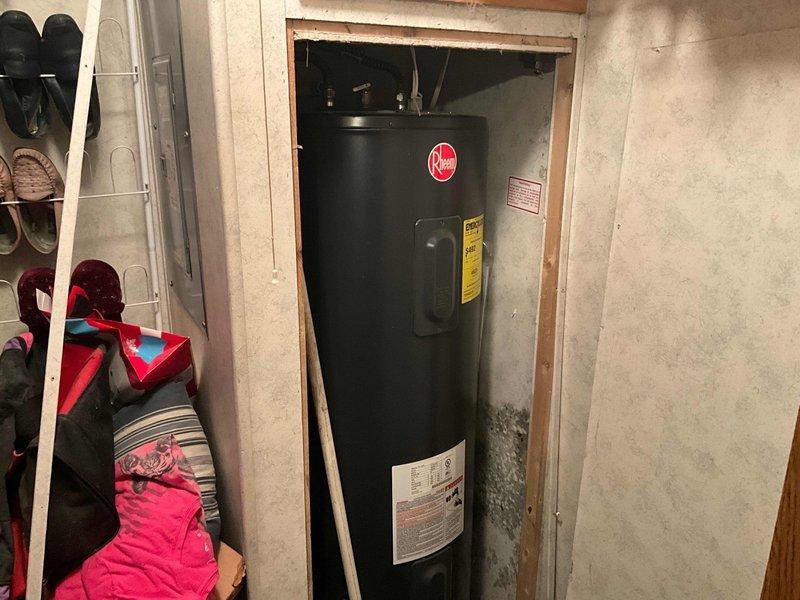 Responded to service call for leaking electric tanked water heater located in basement utility area. Upon arrival, assessed the unit installed in framed opening adjacent to storage space. Took measurements of clearance space and documented existing water heater configuration, including manufacturer specifications and energy guide labels. Photographed unit condition and surrounding installation area to document leak source and determine replacement requirements.