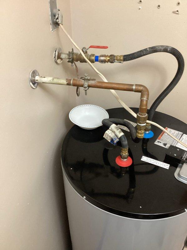 Provided plumbing estimate for connecting customer-installed Whirlpool water softener and water heater on main floor. Assessed existing water heater installation with copper supply lines, brass shut-off valves, pressure relief piping, and flexible hose connections. Evaluated plumbing configuration requirements to integrate water softener system with existing water heater hookup, including necessary valve installations, supply line connections, and proper sequencing of water treatment equipment.