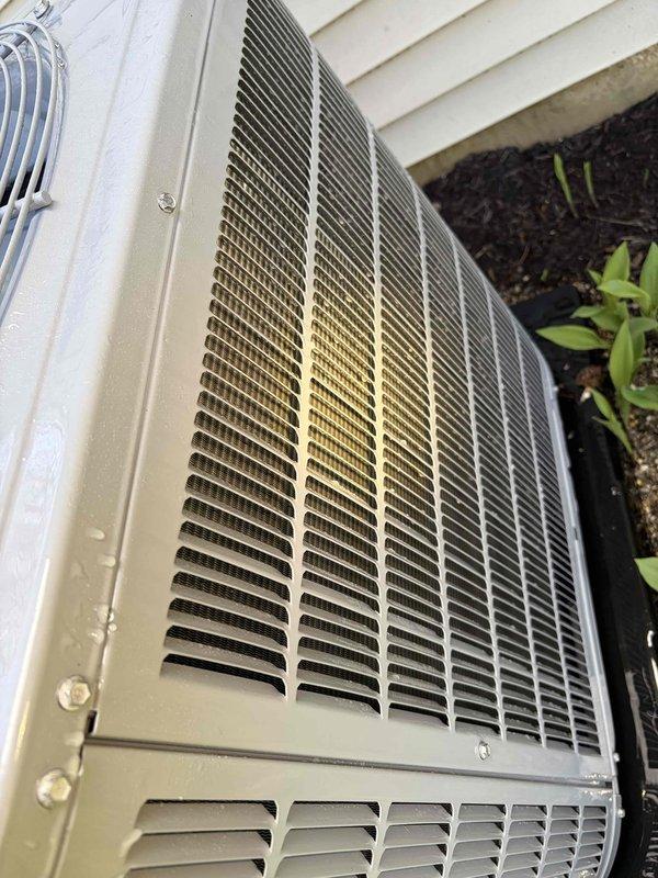 Completed preventive maintenance inspection on Carrier outdoor condensing unit. Performed comprehensive system evaluation including visual inspection of cabinet condition, noting weathering and discoloration on upper grille sections consistent with outdoor exposure. Inspected refrigerant line connections, electrical disconnect, and conduit routing. Verified proper unit mounting and levelness on base pad. Checked fan motor operation and protective grille screening integrity. Confirmed adequate clearance from landscaping and proper airflow around unit perimeter. System operational and maintenance contract extended through expiration date. Unit photographed for service records.