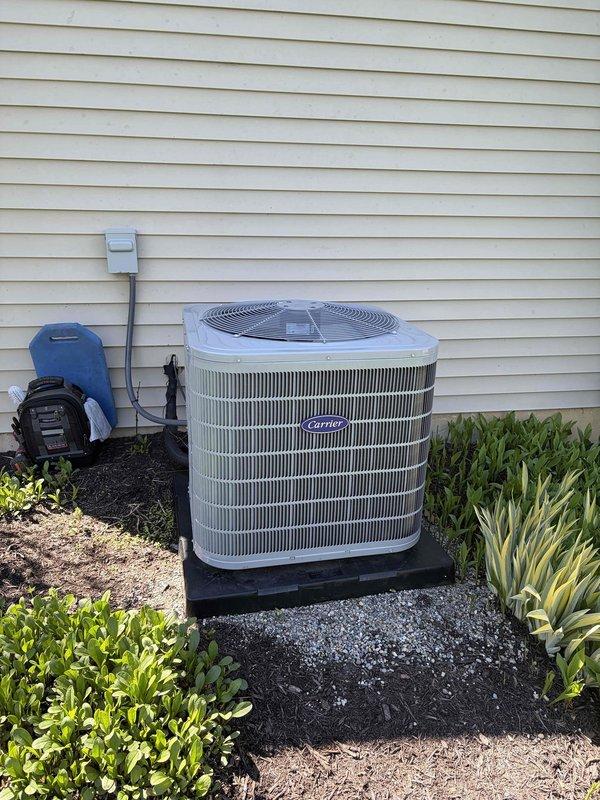 Completed preventive maintenance inspection on Carrier outdoor condensing unit. Performed comprehensive system evaluation including visual inspection of cabinet condition, noting weathering and discoloration on upper grille sections consistent with outdoor exposure. Inspected refrigerant line connections, electrical disconnect, and conduit routing. Verified proper unit mounting and levelness on base pad. Checked fan motor operation and protective grille screening integrity. Confirmed adequate clearance from landscaping and proper airflow around unit perimeter. System operational and maintenance contract extended through expiration date. Unit photographed for service records.