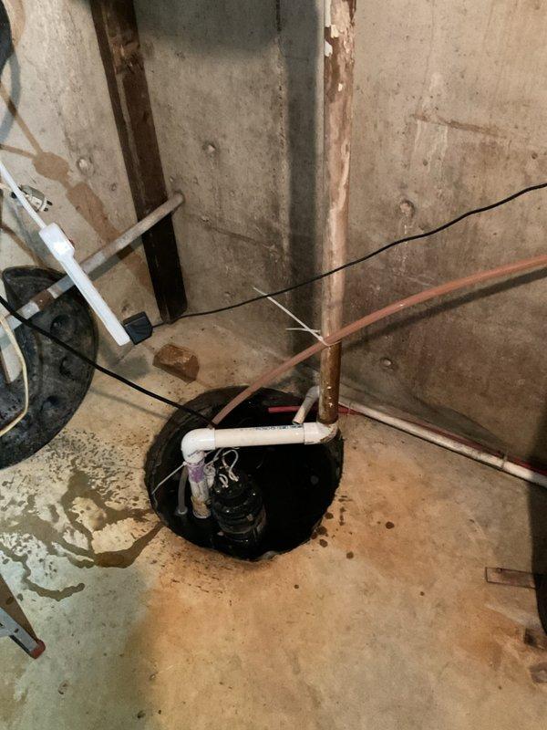 Responded to customer complaint regarding sump pump emitting sewage odor during rain events. Conducted thorough inspection of existing sump pump system in unfinished basement area. Evaluated current basin installation, discharge piping configuration, and overall system adequacy for the property. Documented extensive moisture staining on concrete surfaces and rust discoloration on vertical discharge piping, indicating potential system age and performance issues. Assessed white PVC piping arrangement, including multiple elbow joints and connections to determine proper venting and discharge routing. Identified customer concerns about current system being inadequate for home requirements. Photographed existing conditions showing sump basin, discharge lines, and visible signs of water exposure throughout basement space. Provided professional assessment and prepared replacement quote for upgraded sump pump system to address odor concerns and ensure proper functionality during precipitation e