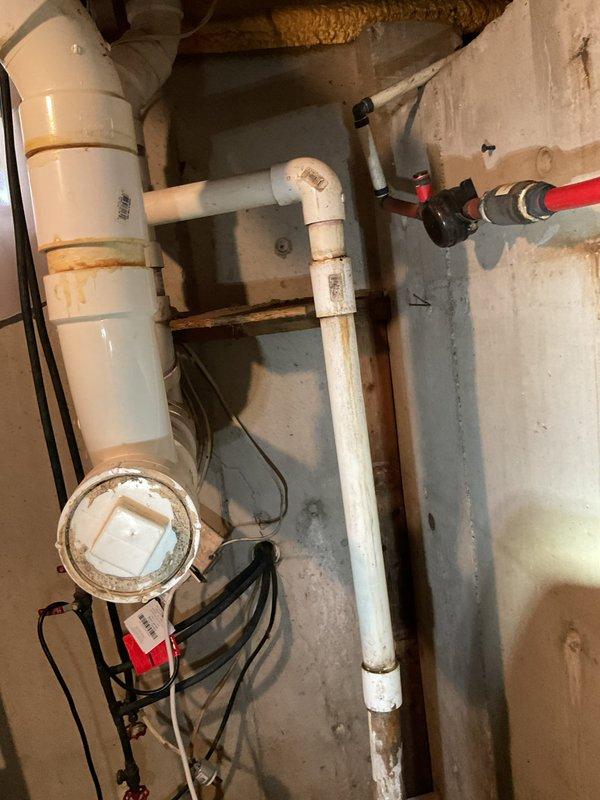 Responded to customer complaint regarding sump pump emitting sewage odor during rain events. Conducted thorough inspection of existing sump pump system in unfinished basement area. Evaluated current basin installation, discharge piping configuration, and overall system adequacy for the property. Documented extensive moisture staining on concrete surfaces and rust discoloration on vertical discharge piping, indicating potential system age and performance issues. Assessed white PVC piping arrangement, including multiple elbow joints and connections to determine proper venting and discharge routing. Identified customer concerns about current system being inadequate for home requirements. Photographed existing conditions showing sump basin, discharge lines, and visible signs of water exposure throughout basement space. Provided professional assessment and prepared replacement quote for upgraded sump pump system to address odor concerns and ensure proper functionality during precipitation e
