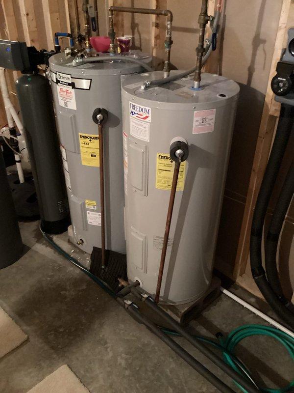 Provided estimate for replacement of leaking water heater serving as storage tank for geothermal hot water assist system. Unit exhibiting leak at base requiring full replacement. Assessed existing dual water heater configuration with interconnected copper piping system and documented current installation with photographs for estimate preparation.