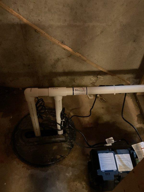 Replaced existing main sump pump with Zoeller M98 model and installed Proflo battery backup system with maintenance-free battery. Removed and hauled away two old pumps from basin. Rerouted discharge piping across basement to exit at rear of home instead of original side location. Capped off two existing 1-1/2" exterior discharge lines with glued PVC caps. Installed new discharge lines with appropriate PVC piping and fittings to accommodate both primary and backup pump systems. Tested both pumps for proper operation and verified battery backup system functionality. All components installed per manufacturer specifications with proper electrical connections and check valve placement to prevent backflow.
