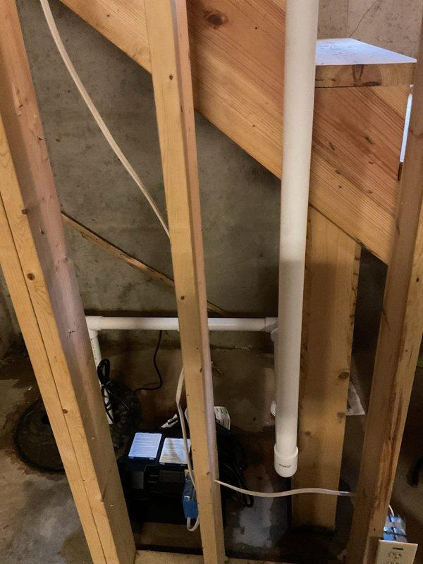 Replaced existing main sump pump with Zoeller M98 model and installed Proflo battery backup system with maintenance-free battery. Removed and hauled away two old pumps from basin. Rerouted discharge piping across basement to exit at rear of home instead of original side location. Capped off two existing 1-1/2" exterior discharge lines with glued PVC caps. Installed new discharge lines with appropriate PVC piping and fittings to accommodate both primary and backup pump systems. Tested both pumps for proper operation and verified battery backup system functionality. All components installed per manufacturer specifications with proper electrical connections and check valve placement to prevent backflow.