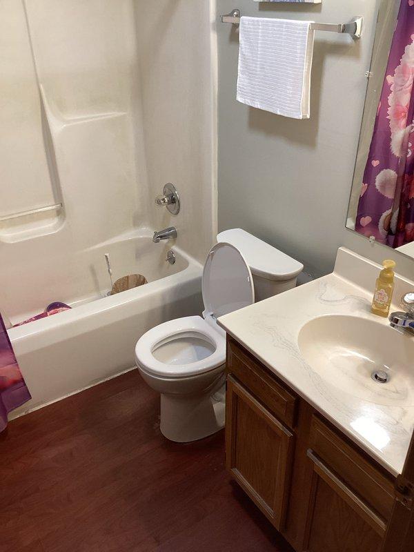 Removed existing toilet and installed new white porcelain toilet in residential bathroom. Secured unit to floor flange with new wax ring seal and closet bolts, reconnected water supply line, and tested for proper operation and leaks. Verified flush mechanism functioned correctly and left work area clean with all fixtures operational.