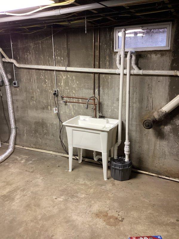 Installed a sewage ejector pump system in the basement to accommodate the relocation of washer and dryer from the main floor. The pump was positioned adjacent to the existing utility sink to handle gray water discharge from the relocated laundry appliances. New PVC drain lines were routed and connected to facilitate proper drainage through the pump system, ensuring compliance with code requirements for below-grade plumbing fixtures.
