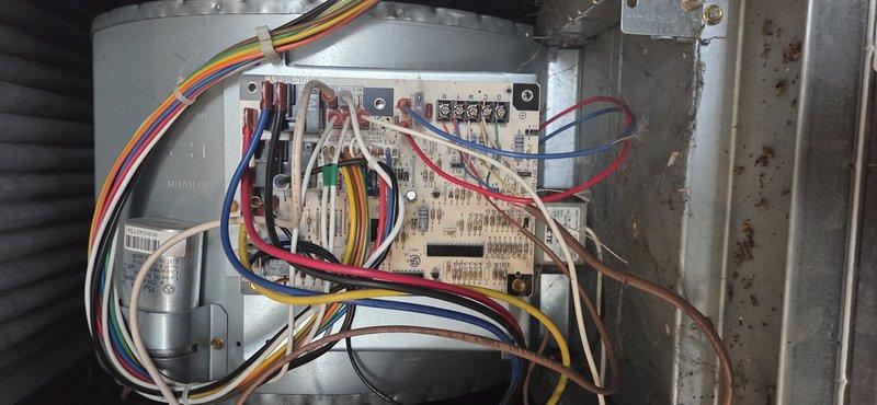 Responded to no heat call on commercial HVAC unit less than 10 years old. Upon inspection, found control board with disorganized wiring and visible corrosion on interior metal surfaces. Inspected electrical connections, terminal blocks, and relay components on control board assembly. Documented existing conditions of blower motor housing, circuit board wiring, and overall system components for service records.