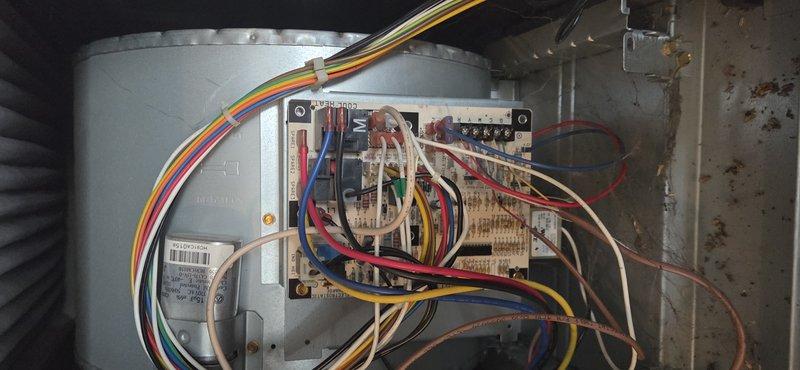 Responded to no heat call on commercial HVAC unit less than 10 years old. Upon inspection, found control board with disorganized wiring and visible corrosion on interior metal surfaces. Inspected electrical connections, terminal blocks, and relay components on control board assembly. Documented existing conditions of blower motor housing, circuit board wiring, and overall system components for service records.