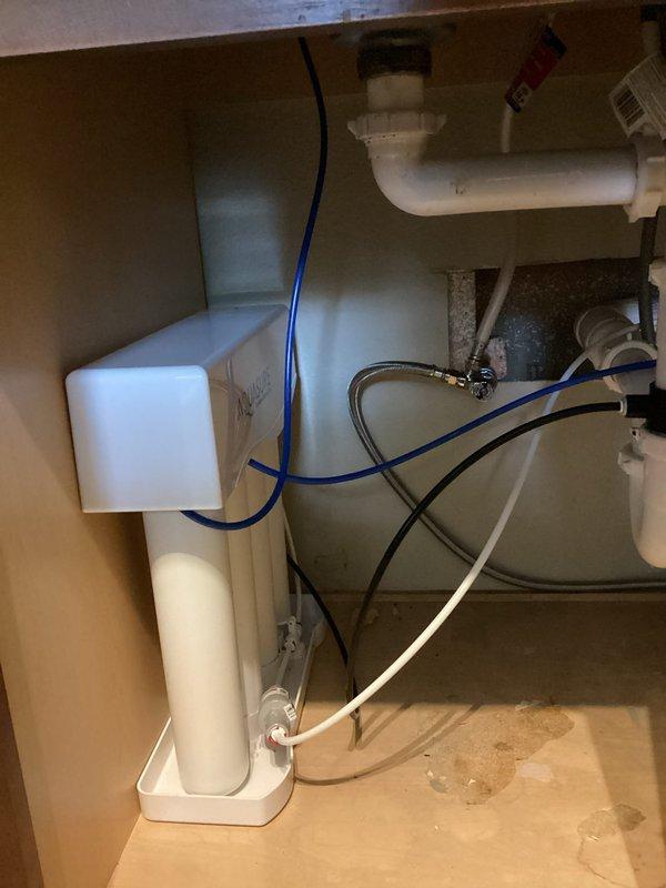 Completed installation of customer-provided reverse osmosis water filtration system under kitchen sink, including all necessary connections and supply lines. Replaced shut-off valve to washing machine with customer-provided valve. Installed new trap assembly to kitchen sink using customer-provided parts, ensuring proper drainage and seal connections.