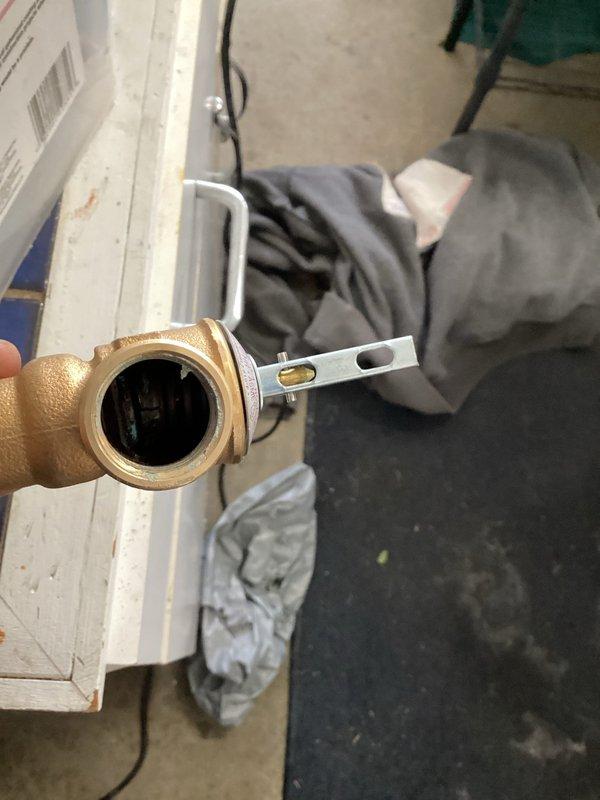 Responded to emergency call for water heater pipe leak that customer was unable to stop. Upon arrival, assessed the leaking brass valve assembly connected to the water heater system. Removed and replaced the defective T-shaped brass valve fitting with new component, ensuring proper alignment using level tool during installation. Verified all connections were secure, tested system for leaks, and confirmed proper operation of the shut-off valve. System restored to full functionality with no active leaks detected.
