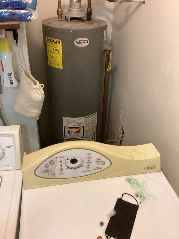 Responded to no hot water complaint on residential natural gas tanked water heater. Inspected Richmond brand 40-gallon atmospheric vent water heater (model GCWU-40, manufactured October 2013) located in utility room behind dryer. Performed diagnostic assessment of unit, verified gas supply, checked pilot light operation, and inspected burner assembly and thermocouple. Evaluated flue venting system and temperature pressure relief valve for proper operation. Documented equipment condition and safety label compliance with photographs for service records.